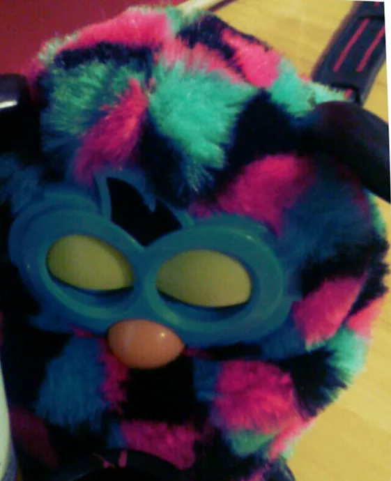 Sleeping Furby Boom with pink, teal and black triangle-patterned fur and a blue faceplate.